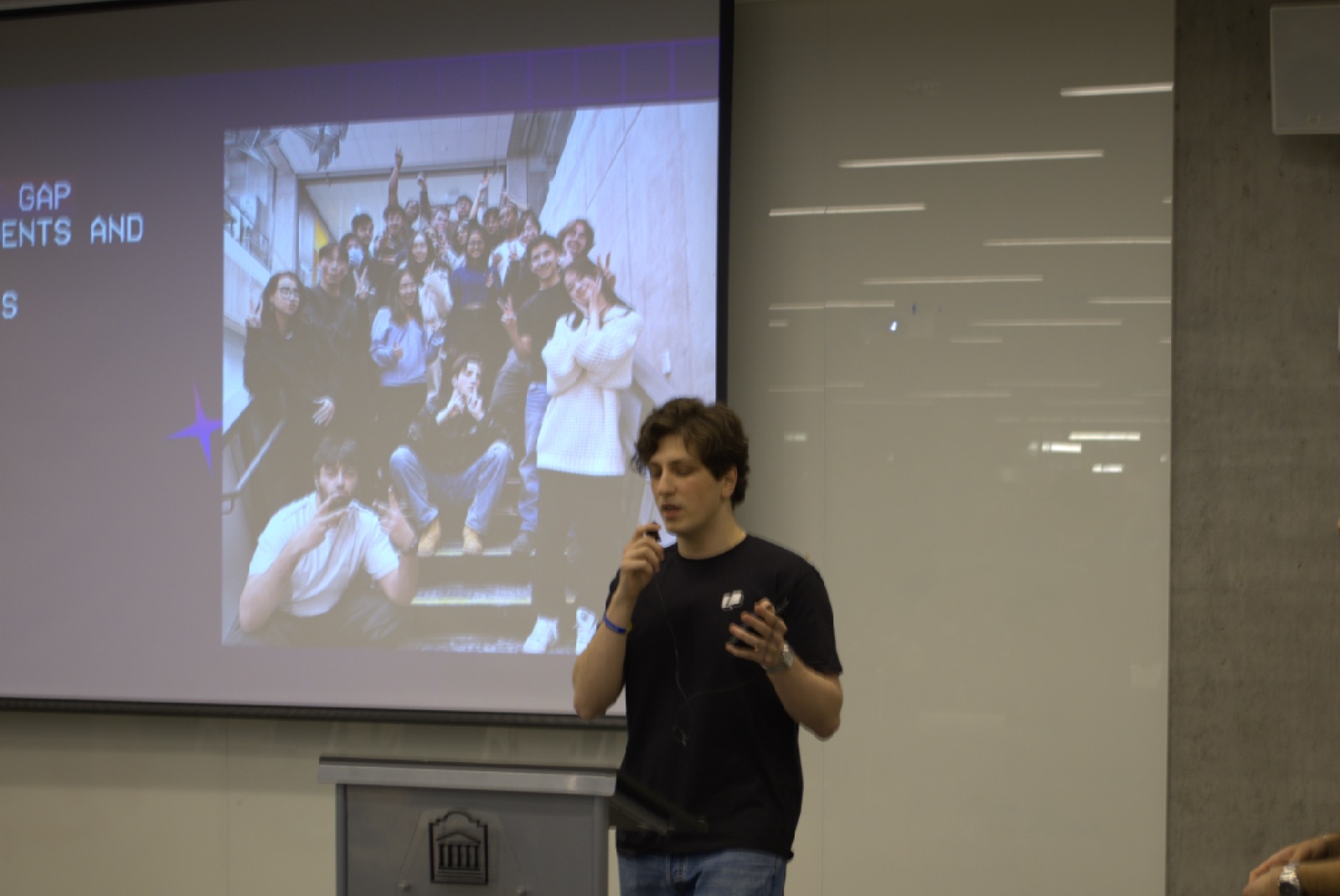 rolf speaking into a mic beside the sesa intro slide at the sesa x warp workshop